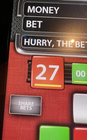 A digital display screen showing a casino betting interface, with text prompting to hurry bets and a highlighted number 27 in red. There are options for betting amounts and a 'share bets' button.
